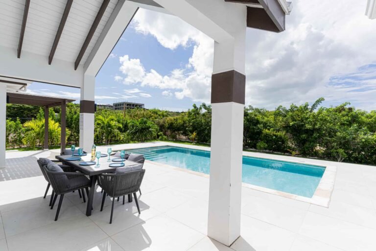 Shaded outdoor patio with dining table and views of the private swimming pool.