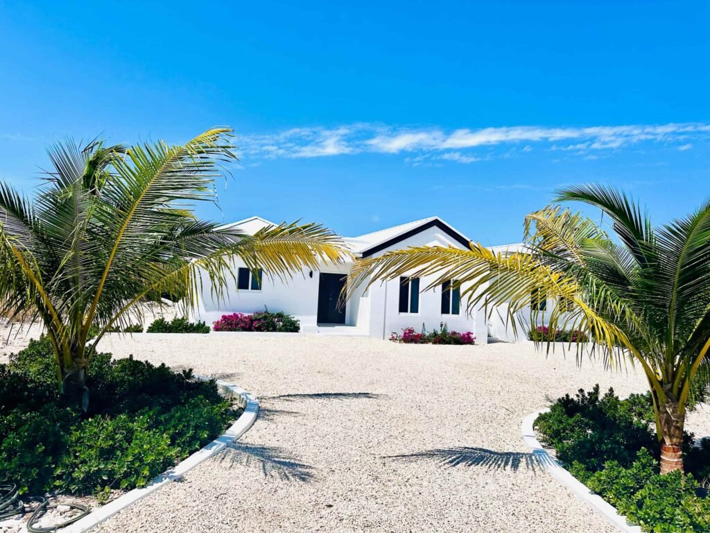 Front exterior of Blue Water Villa featuring tropical landscaping and a spacious driveway in Grand Turk.